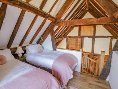 A bedroom with two single beds and wooden beams in the ceiling at Munderfield Mill in Munderfield near Bishops Frome
