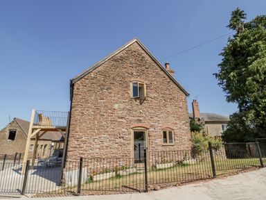 A stone house with small windows and a gated yard at Munderfield Mill in Munderfield near Bishops Frome
