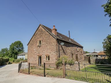 A stone cottage with a gated yard and a concrete driveway at Munderfield Mill in Munderfield near Bishops Frome