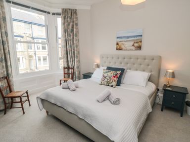 A bedroom with a bed with towels on it two chairs by a window and bedside tables with lamps at Spinnaker House in Scarborough