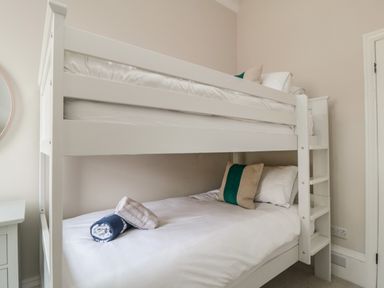 A bedroom with a white bunk bed with pillows and folded towels at Spinnaker House in Scarborough