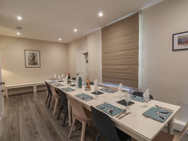 A dining room with a long white table set for ten with placemats and chairs at Spinnaker House in Scarborough