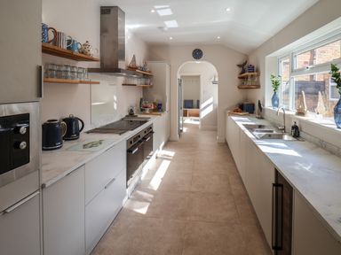 A kitchen with countertops on both sides appliances on the left and a window on the right at Spinnaker House in Scarborough