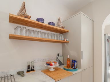A kitchen corner with wooden shelves holding glasses and decorative items at Spinnaker House in Scarborough