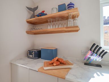 A kitchen counter with croissants on a wooden board a toaster a bread box and a knife set at Spinnaker House in Scarborough