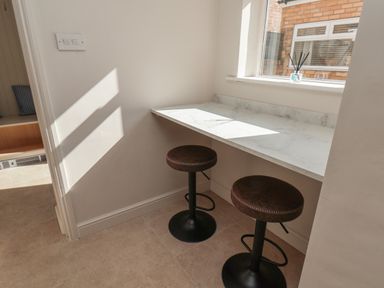 A corner with a marble countertop and two brown bar stools near a window at Spinnaker House in Scarborough