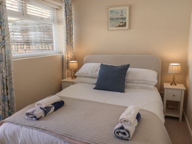 A bedroom with a bed with white bedding and blue cushions and two bedside tables with lamps at Spinnaker House in Scarborough