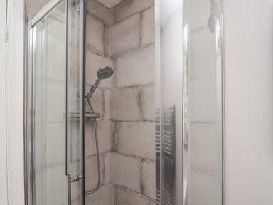 A shower area with glass doors and a handheld showerhead with tiled walls at Spinnaker House in Scarborough