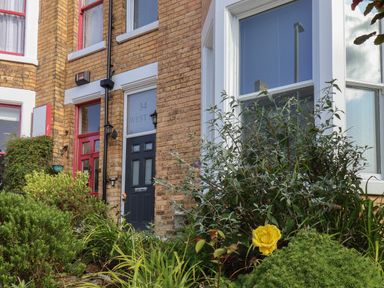 Exterior of a brick building with two doors one black and one red and plants in front at Spinnaker House in Scarborough