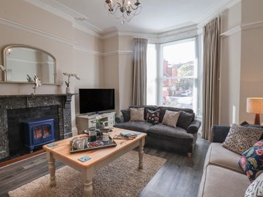 A living room with two sofas a wooden coffee table a TV and a fireplace at Spinnaker House in Scarborough