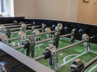 A foosball table with metal players on rods in a room with a window at Spinnaker House in Scarborough