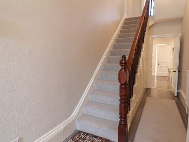 A carpeted staircase with a wooden banister and a hallway with doors at Spinnaker House in Scarborough