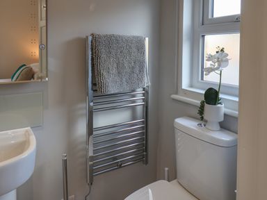 A bathroom with a towel hanging on a heated towel rail a toilet with a plant on the cistern and a sink at Spinnaker House in Scarborough