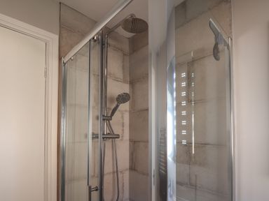 A shower with glass doors and tiled walls in a bathroom at Spinnaker House in Scarborough