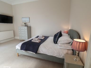A bedroom with a bed pillow lamps and a chest of drawers at Spinnaker House in Scarborough
