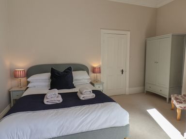 A bedroom with a double bed lamp tables wardrobe and chair at Spinnaker House in Scarborough