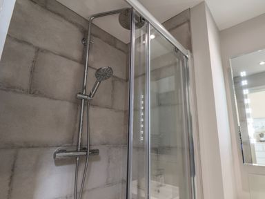 A shower enclosure with a glass door and a chrome showerhead at Spinnaker House in Scarborough