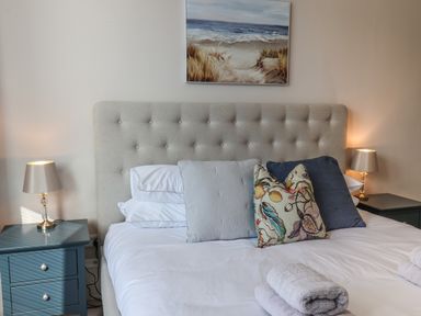 A bedroom with a bed with pillows and folded towels and two bedside tables with lamps at Spinnaker House in Scarborough