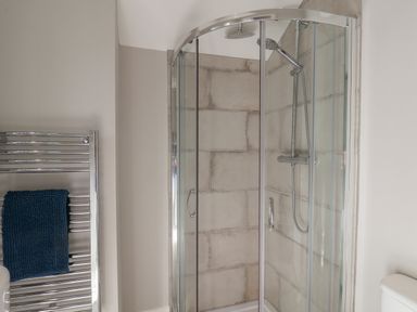 A bathroom with a glass shower enclosure and a chrome towel rack with a blue towel at Spinnaker House in Scarborough