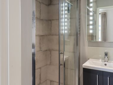 A bathroom with a tiled shower enclosure and a sink with a mirror above at Spinnaker House in Scarborough
