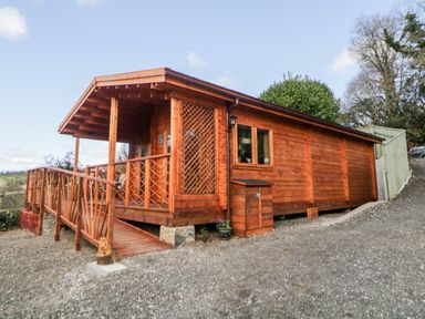 A wooden cabin with a ramp and porch in an outdoor setting at Bearscombe View in Modbury