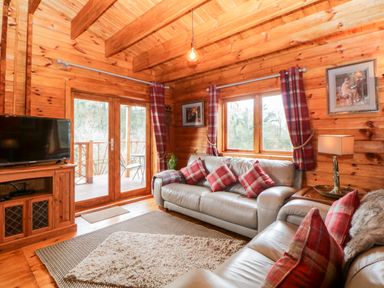 A living room with leather sofas and plaid cushions at Bearscombe View in Modbury