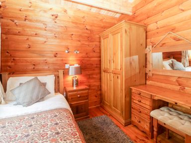 A bedroom with a bed side table with lamp wooden wardrobe dressing table with chair and mirror at Bearscombe View in Modbury
