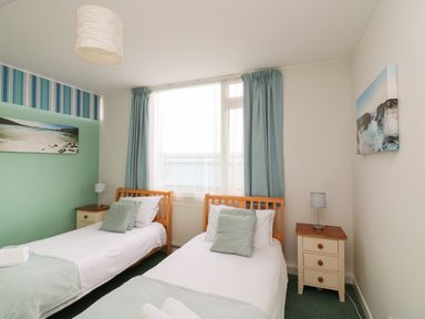 A bedroom with two single beds bedside tables and lamps at Fairway Lodge in Bigbury-On-Sea