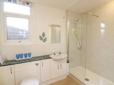 A bathroom with a shower enclosure sink toilet and a window at Fairway Lodge in Bigbury-On-Sea