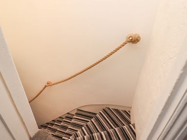 A stairwell with striped carpeted stairs and a rope handrail attached to a wall at Monteva in Whitby