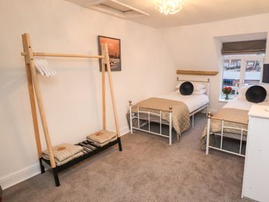 A bedroom with two single beds pillows and blankets wooden clothes rack with hangers and folded blankets at Monteva in Whitby