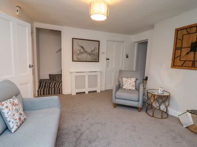 A living room with gray sofas and armchairs a glass side table and a wall clock at Monteva Whitby