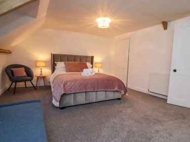 A bedroom with a bed with pink bedding two bedside tables with lamps a chair and a door at Monteva in Whitby