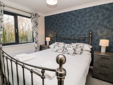 A bedroom with a metal bed frame and bedside tables with lamps at Mayflower in Broadwoodwidger near Ashwater