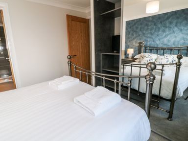 A bedroom with a bed with folded towels on it a wooden door a mirrored wardrobe and a bedside table with a lamp at Mayflower Broadwoodwidger near Ashwater
