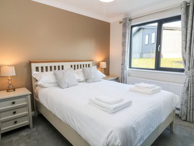 A bedroom with a bed two bedside tables lamps and a window with curtains at Mayflower Broadwoodwidger near Ashwater