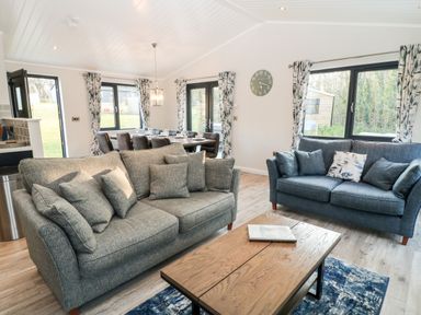A living room with two sofas a wooden coffee table a dining table with chairs and large windows at Mayflower Broadwoodwidger near Ashwater