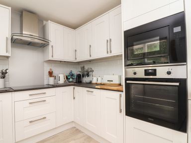 A kitchen with white cabinets black countertop stainless steel oven and microwave at Penpoll Little Petherick Creek near Padstow
