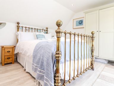 A bedroom with a brass bed frame a wooden nightstand and a white wardrobe at Penpoll Little Petherick Creek near Padstow
