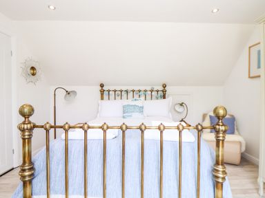 A bedroom with a brass bedframe a blue blanket and a chair with cushions at Penpoll in Little Petherick Creek near Padstow