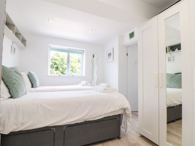 A bedroom with two single beds white wardrobe and window at Penpoll Little Petherick Creek near Padstow