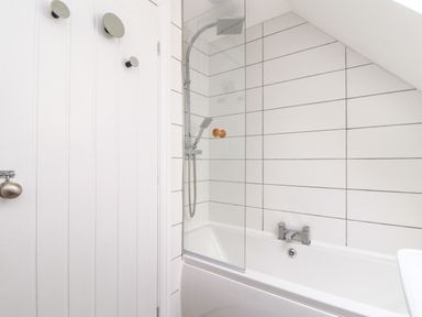 A bathroom with a bathtub shower and tiled walls at Penpoll in Little Petherick Creek near Padstow