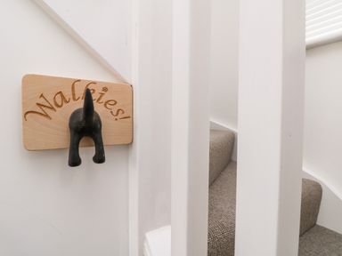 A wooden sign with a dog tail hook and the word Walkies near carpeted stairs at Penpoll in Little Petherick Creek near Padstow