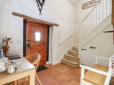 An entryway with a wooden door a small staircase a wooden table and chairs at The Old Barn in Colyton