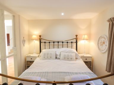 A bedroom with a double bed two bedside tables with lamps and decorative pillows at The Old Barn in Colyton