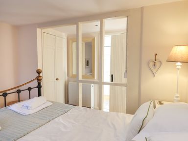 A bedroom with a bed folded towels a lamp and a heart decoration on the wall at The Old Barn in Colyton