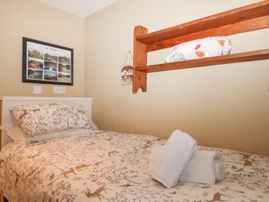 A single bed with deer patterned bedding and towels on top in a small bedroom at The Old Barn in Colyton