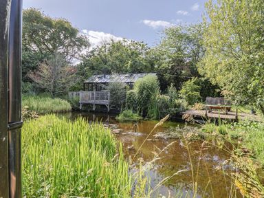 A garden with a pond and deck seating at The Old Barn in Colyton