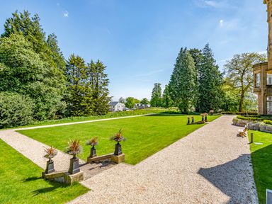 A garden with a gravel pathway lawn and trees at Alice House Stone Cross Mansion in Ulverston