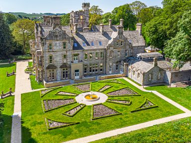A large stone mansion with a central flower garden and surrounding pathways at Alice House Stone Cross Mansion in Ulverston